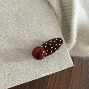 Detailed macro of vintage red polka dot hair clip with a glossy bead design element