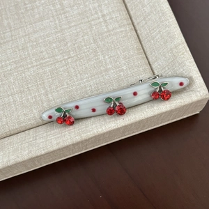 Detailed macro of a resin cherry hair clip with red rhinestones on a linen tray