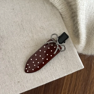 Detail of red polka dot hair clip with silver bow and dark alloy duckbill clamp