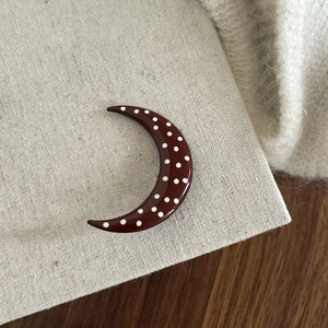 Close-up of vintage crescent red hairpin with white polka dots on rustic linen fabric