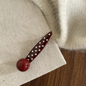 Detail of vintage red polka dot hair clip with large round bead on a textured base