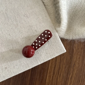 Vintage red polka dot hair clip with asymmetrical design for women on woven fabric