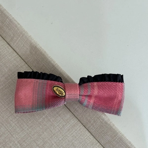 Detail of pink plaid bow hair clip with black lace trim and golden 'love' emblem