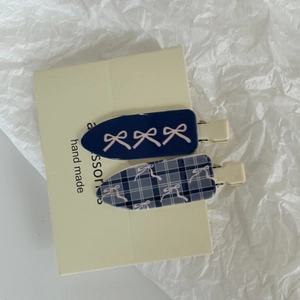 Détail de barrettes à carreaux bleus avec motifs nœuds roses sur carte beige