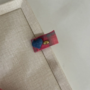 Detail of pink plaid hair clip with blue denim heart and vintage gold 'love' metal charm