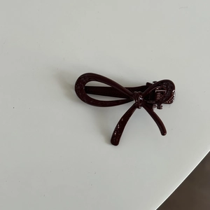 Detailansicht einer glänzend tiefroten Schleife Haarspange aus Metall mit Entenschnabel
