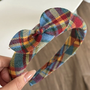Detailed texture of a yellow and blue plaid headband featuring a classic bow design