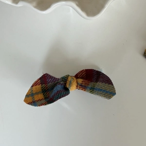 Detailed view of vintage plaid bow hair clip with yellow and blue checkered fabric texture