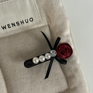 Macro detail of vintage red rose hair clip with white pearls and luxury satin bow