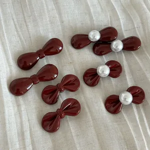 Set of 7 deep red bow hair clips with white pearls on a natural linen background