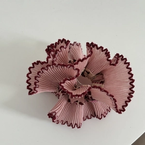 Macro shot of pink pleated scrunchie showing fine textures and burgundy wavy lace edges