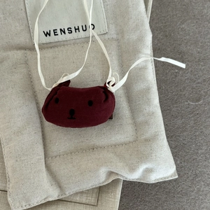 Détail du mini sac en tissu rouge foncé avec broderie ours et attaches en coton blanc