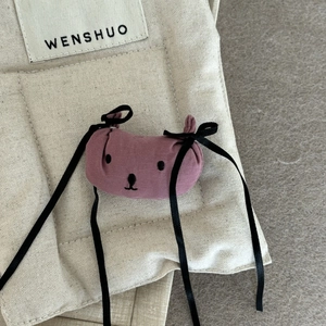 Détail d'une pince à cheveux chien rose poudré avec nœuds en soie noire et tissu doux