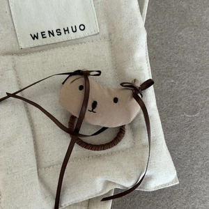 Détail d'un élastique à cheveux en peluche fait main en forme de chien sur lin