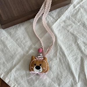 Detaillierte Nahaufnahme von handgefertigtem Teddybär-Anhänger mit rosa gepunktetem Hut