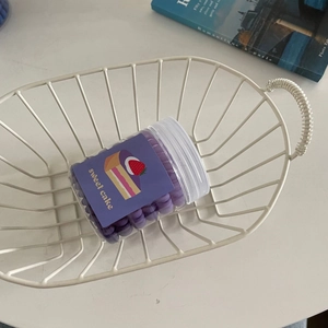 Pot de perles de cire violettes pour sceaux dans un panier décoratif en métal blanc