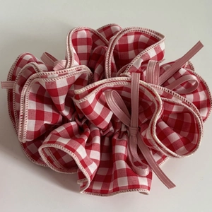 Red and white checkered hair scrunchie with pink silk ribbon bow on white background