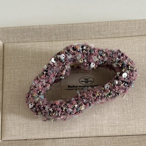 Détail des paillettes sur le tissu en laine mélangée texturée de la pince à cheveux