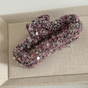 Gros plan sur une pince à cheveux en tweed bouclé rose ornée de paillettes