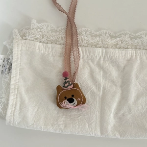 Detail der handgefertigten braunen Bärenstickerei mit Spitze und rosa Partyhut-Verzierung