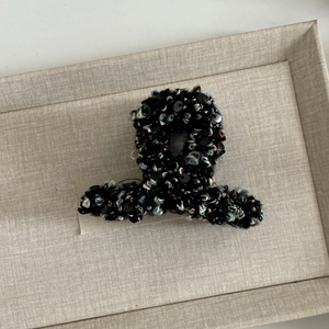 Détail de la pince à cheveux en tweed haut de gamme avec paillettes noires sur plateau
