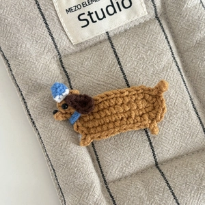 Nahaufnahme der handgehäkelten braunen Dackel-Haarspange mit blauem Hut-Detail