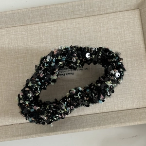 Vue détaillée d'un chouchou en peluche à paillettes noires sur un plateau tressé