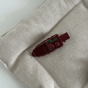 Vue détaillée d'une barrette à carreaux avec ornement cerise en 3D et feuilles vertes