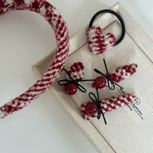 Close-up of a 5-piece red tweed hair accessory set with pearls and bows on a jewelry box