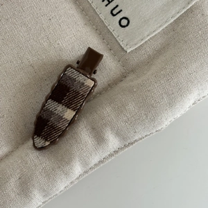 Gros plan d'une pince à cheveux rétro à carreaux marron sur une surface en toile beige