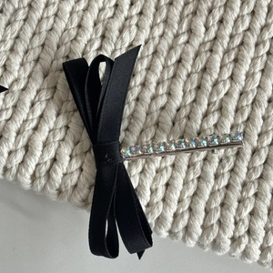 Detailed view of layered black satin bow hair clip with sparkling colorful rhinestones