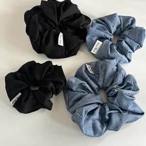 Close-up of denim blue and black polka dot scrunchies with white Hand Made labels