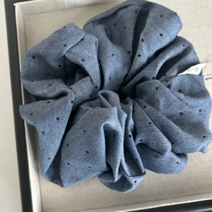 Denim blue fabric scrunchie with black polka dots shown in a beige display box