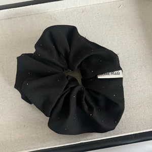 Macro shot of black fabric scrunchie with sparkly sequins and a Hand Made label detail