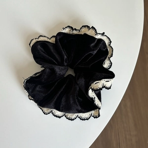 Détail d'un chouchou en dentelle avec tissu noir et bords en crochet crème élégants