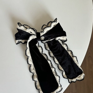 Chouchou en velours noir avec nœud en dentelle blanche et bouton en métal argenté