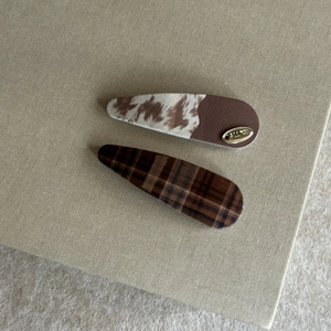 Set of two leopard print and cow pattern acrylic hair clips with gold metal logo tag