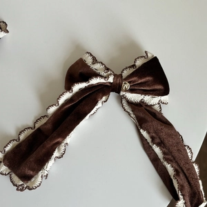 Détail d'un chouchou en velours avec dentelle marron et ornement en métal doré chic