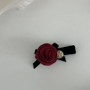 Vue macro de la pince à cheveux rose en satin rouge avec relief doré et ruban noir