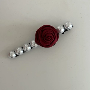 Vue détaillée d'une pince à cheveux vintage avec rose en tissu rouge et perles blanches
