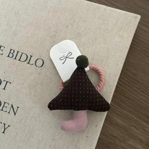 Detail of Christmas tree fabric hair tie with plush ball and pink woven rope on a book