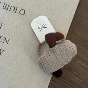 Close-up of a handmade 3D umbrella hair clip with plush heart element and white logo card