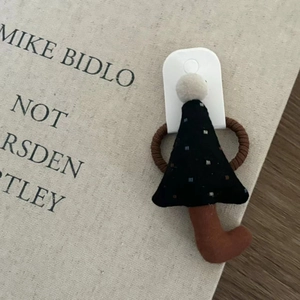Detailed view of a black plush Christmas tree hair tie on a decorative book background