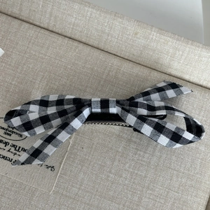 Detail of a chic black and white checkered bow hair clip with a vintage French aesthetic