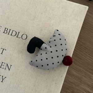 Detail view of plush umbrella hair clip with retro polka dots and red pom-pom decor