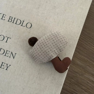 Detailed view of a handmade 3D mushroom fabric hair clip on a vintage book page backdrop