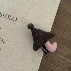 Detail shot of a handmade mushroom-shaped plush hair clip with brown polka dot fabric