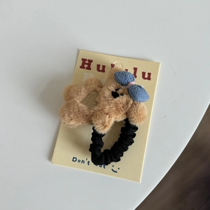 Détail d'un élastique à cheveux ours en peluche marron avec nœud bleu et broderie cœur