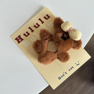 Détail d'accessoire cheveux ours en peluche marron avec nœud jaune sur carton