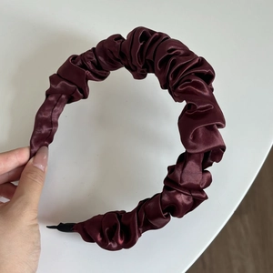 Detail view of cherry red satin headband with vintage pleated texture and non-slip tip